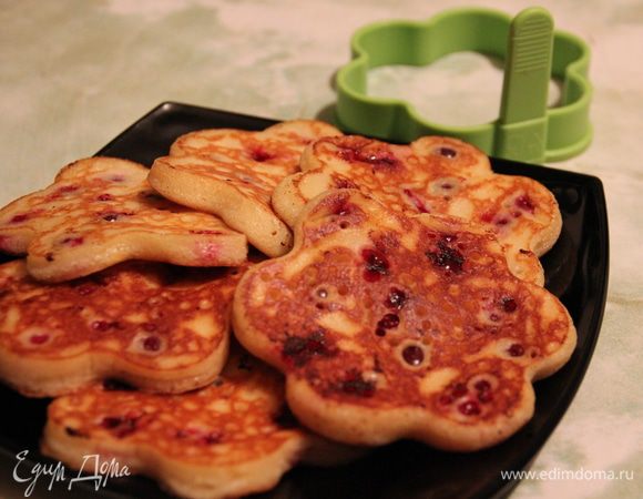 Разогреть сковороду, смазать сливочным маслом, в цент сковороды поместить силиконовую форму в виде цветочка. Заполнить ее на 1/2 тестом, посыпать клюквой, слегка вдавливая ее в тесто. Обжаривать до схватывания верхнего слоя оладушка, после чего аккуратно снять форму, перевернуть оладушек и жарить с другой стороны до золотистого цвета.