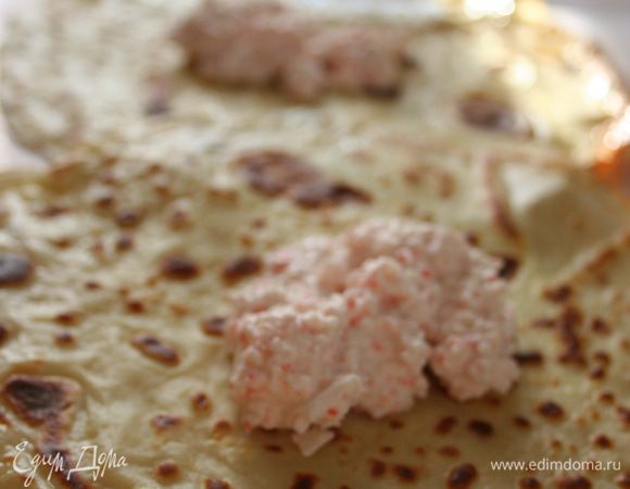 Намазывает блинчики начинкой. 