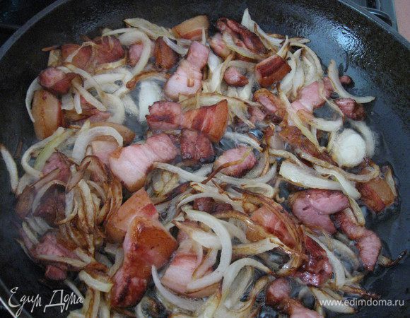 Лук режем полукольцами, добавляем к бекону, продолжаем жарить.