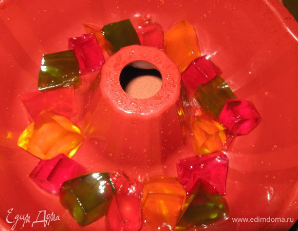 Перемешиваем и тонкой струйкой вводим в творожно- сливочную массу,постоянно перемешивая. Смачиваем форму, кладем  в нее кубики желе. 