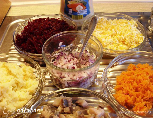 Филе сельди обмыть и обсушить. Лук почистить. Сельдь и лук мелко нарезать на кубики размером 0.5х0.5х0.5 см.
Яйца отварить, охладить, почистить и натереть на мелкой тёрке.
Картофель, морковь и свёклу почистить, помыть и спецконтейнере для СВЧ сварить в микроволновке. Остудить и натереть на мелкой терке.