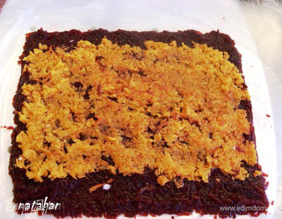 Выложить слой моркови на слой свёклы: сверху и снизу отступить от границы свёклы на 2.5-3 см, а на торцах прямоугольника границы слоёв должны совпадать. Уплотнить овощи через целлофан.