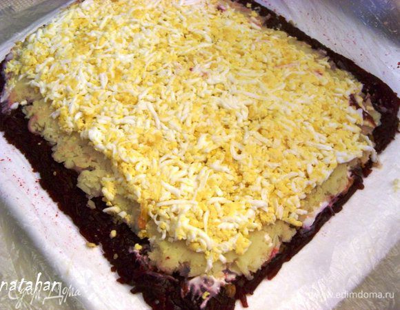 На картофельный слой выложить протертые через мелкую терку яйца, также уменьшая высоту прямоугольника и оставляя неизменной его длину. Яичный слой закрыть целлофаном и ладошкой утромбовать.