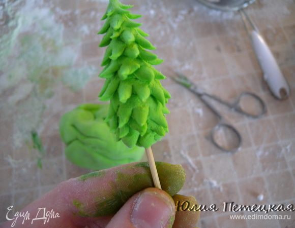 Сделайте 1 елочку — остальная мастика завернута в фольгу. Если нужно, разогрейте в микроволновке. Елочки — на зубочистках.