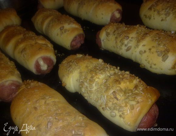 сосиски прорезать вдоль не до конца, вставить в полученную прорезь ломтик сыра, завернуть полученное в полоску приготовленного теста, с одной стороны обвалять в семенах подсолнечника или кунжуте. Выпекать примерно 25 минут, пока не зарумянятся. Вуаля!