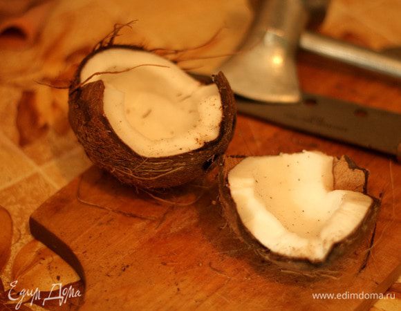 Скорлупу разбить. Я с помощью ножа, сделала трещины на кокосе, потом била молотком и трещинки увеличивались. 
Отделить мякоть от скорлупы, ножом срезать коричневую оболочку. Белую мякоть натереть на крупной терке или можно измельчить в процессоре.

