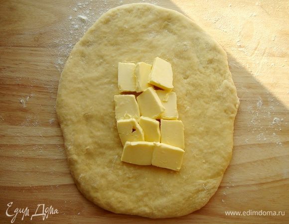 Раскатать тесто в пласт, в середину положить сливочное масло кусочками.