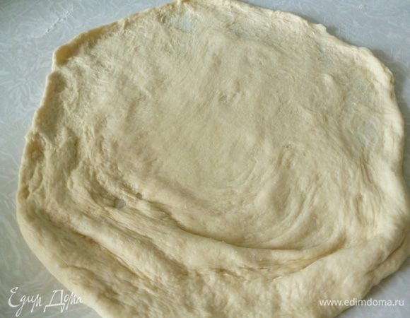 Теперь будем растягивать лепешку в тонкий корж. Руки кладем под тесто и сначала аккуратно растягиваем пальцами середину лепешки от центра к краям. Доска для разделки должна быть широкой. Я для этой цели использую столешницу от старого кухонного стола.