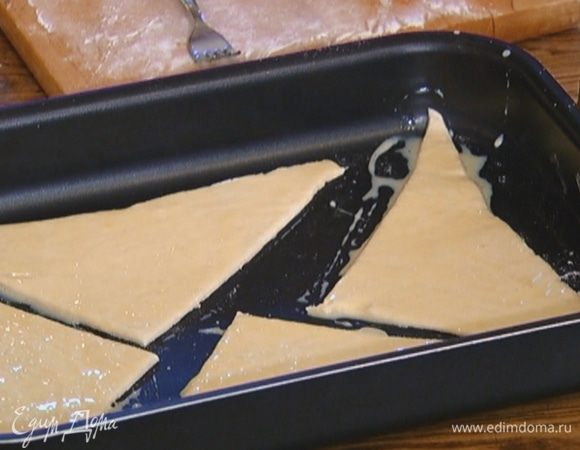 Выложить треугольники на противень, смазать их яйцом с молоком и присыпать 1 ч. ложкой сахара.