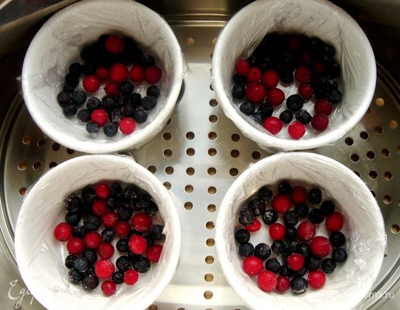 Жаропрочные формочки застелить пищевой плёнкой, а лучше смазать маслом. В каждую форму положить по горсти ягод (у меня черника и клюква).