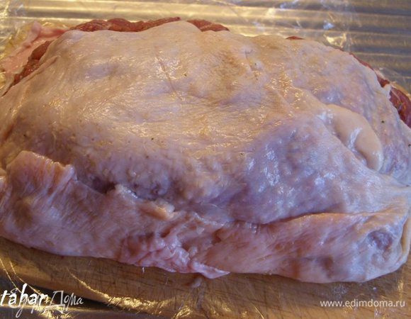 На середину разделочной доски, покрытой кожей, выложить весь фарш, уплотнить его и аккуратно закрыть кожей с одной стороны (помогая руками через целлофановую плёнку).