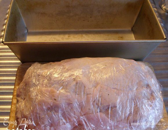 Повернуть доску на 180 градусов и закрыть фарш кожей с другой стороны. Целлофановой плёнкой обернуть ветчину и сформировать её по размерам формы, в которой будем запекать (у меня хлебная).