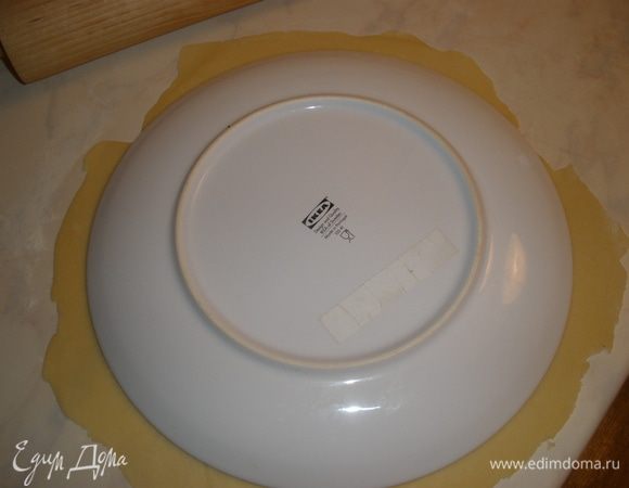 Тесто разделить на 2 части - одна побольше это будет основа и оставшееся для полосок. Основу раскатать в круг и обрезать по форме большого блюда, для того чтобы края были ровными. Зарарнее нарезать полоски, я сделала 9 штук широких. 