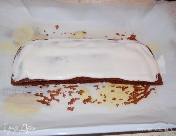 Собираем торт. Одну половинку темного коржа положить на бумагу (или фольгу) *размер бумаги должен быть с запасом*... Смазать небольшим количеством крема.