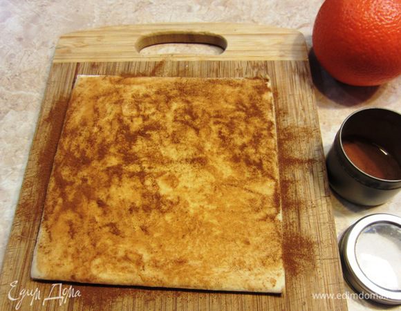 Разморозьте тесто. Для этого я положил тесто на разделочную доску и накрыл пакетом. Посыпьте сверху на тесто корицу и распределите пальцами по поверхности