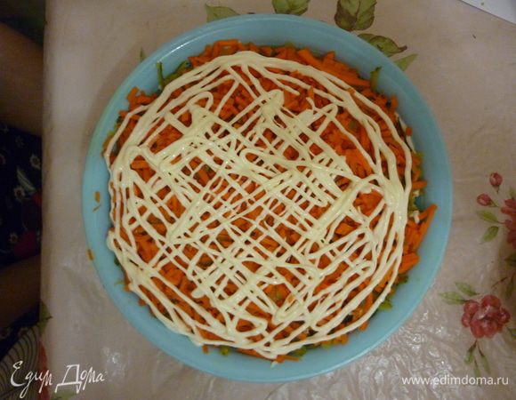 Затем на крупную терку трем морковку, выкладываем и прижимаем слой к уже имеющимся. Делаем майонезную сетку.