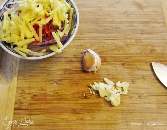 Ударьте плоской стороной ножа по чесноку, чтобы кожица лопнула. Так будет очень легко снять ее. Срежьте попку, разрежьте вдоль зубчик, а потом поперек довольно мелко.
