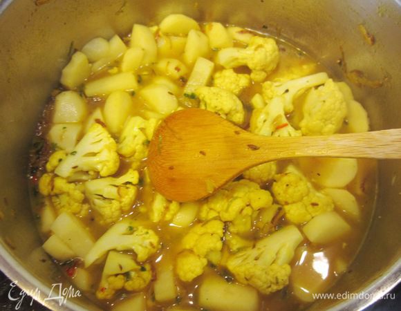 Добавьте в кастрюлю картофель, капусту и кокосовую стружку. Залейте все 400 миллилитров кипятка. Посолите и поперчите. Доведите до кипения, накройте крышкой и варите на медленном огне минут 15-20 - до мягкости овощей.