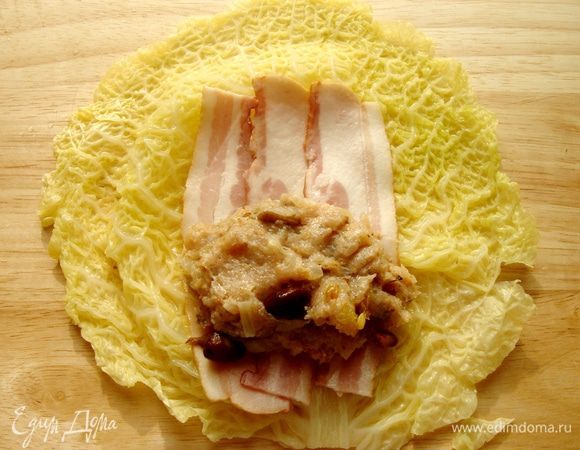 На капустный лист выложить полоску бекона,разрезанную поперёк на две части,а на бекон-фарш.Свернуть голубец.