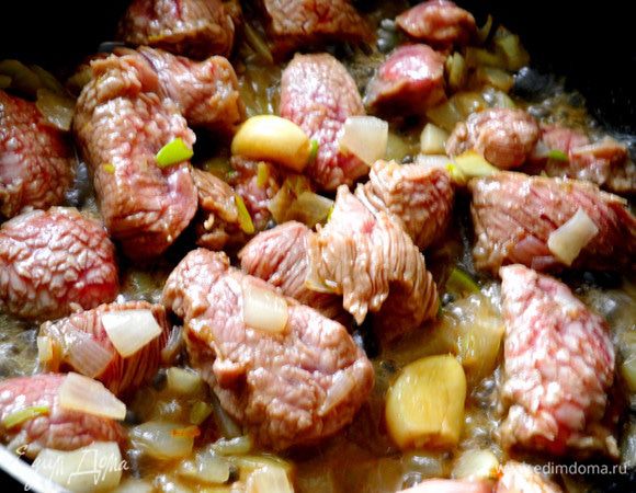 Лук очистить и мелко нарезать. Чеснок, не очищая, слегка раздавить. В глубокой сковородке или сотейнике разогреть масло и обжарить лук и чеснок. Затем вынуть мясо из апельсинового "маринада" и обжарить его слегка.