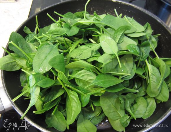 Поставьте снова сковороду на средний огонь. Налейте оливковое масло и высыпьте туда один пакет шпината. Сразу начните переворачивать листья. Они очень быстро потеряют объем. Когда уже будет позволять объем, высыпьте второй пакет шпината.