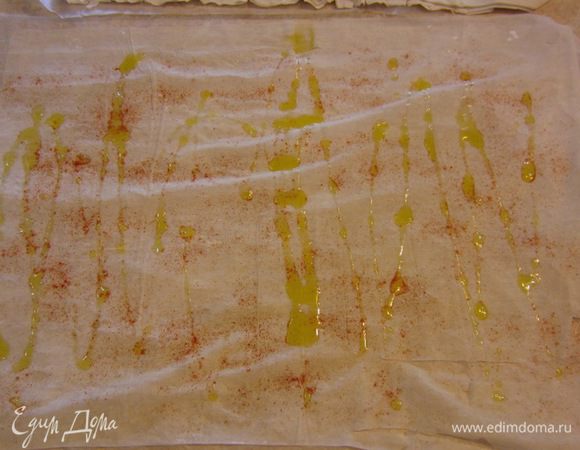 Теперь займемся подготовкой теста. Возьмите большой кусок пергаментной бумаги - сантиметров семьдесят. Намочите ее и слегка сомните. В итоге у вас получится мягкая мокрая бумага. Постелите ее на стол, пусть прилипнет. Смажьте сверху оливковым маслом. Постелите тесто фило. В итоге вам необходимо будет сделать квадрат, размером 50 на 50 сантиметров. Я стелил два листа внахлест. Джейми стелил четыре, т.к. у него были листы меньшего размера. Полейте слегка сверху тесто оливковым маслом и посыпьте красным перцем и немного солью. Слегка распределите масло пальцами.