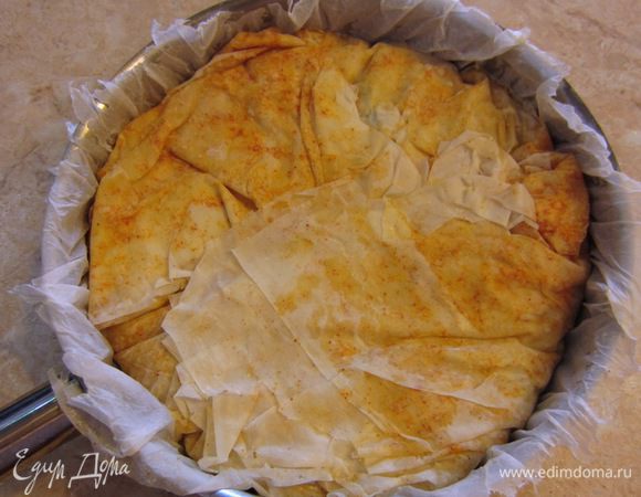 Теперь аккуратно отделите тесто от бумаги и сложите его поверх начинки, как это показано на фотографии. Оборвите бумагу по краям, чтобы она не сгорела. Бумага снизу запеканки предохранит ее от подгорания.