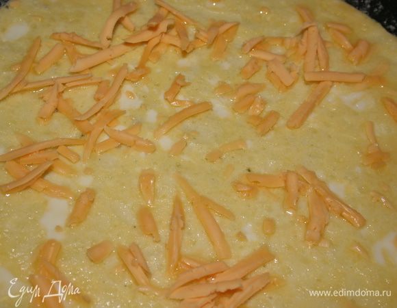 Как только омлет начнет запекаться по краям, примерно через 3-5 минут, посыпаем 1/4 тертого сыра. 