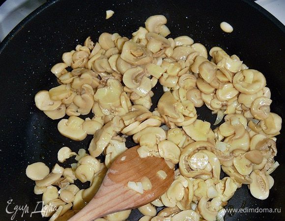 Добавляем грибы. Даем минуту-две прогреться и пропитаться ароматом чеснока. У меня шампиньоны консервированные (стерилизованные с добавлением соли, уже порезанные). Мне такие больше нравятся, потому-что они уже готовые, не пускают сок, остаются мясистыми и просто вкусные. Если у вас свежие, то жарьте их, пока не испарится влага.   