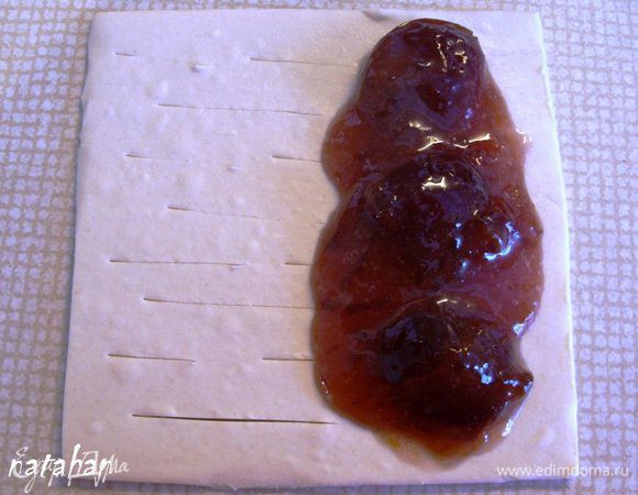 Смешать сливовый конфитюр и крахмал. У оставшихся 6 пластов левую половину надрезать поперек через 1 см не доходя до края на 1 см. А на правую половинку выложить по 4 половинке слив из конфитюра и по 2 ч.л. сливового желе с крахмалом. Разровнять его по половинке пласта не доходя до края на 1 см. Левой половинкой пласта накрыть правую и соединенные края аккуратно пройти плашмя зубчиками вилки. Перенести слойки на противень, застеленный пекарской бумагой.