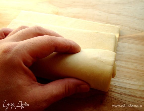 Листы слоёного теста сложить друг на друга,немного сдвинув к себе верхний слой.Свернуть тесто в рулет.Если слоёное тесто свёрнуто в рулон,то надо разморозить его не разворачивая.