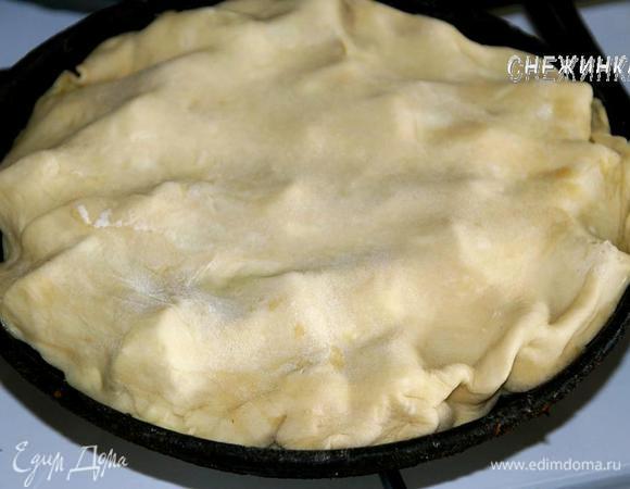 Слоеное тесто раскатать на присыпанной мукой поверхности в круг, чтобы он был чуть шире сковороды и толщиной где-то 3 мм. Накрыть яблоки тестом, слегка подоткнув края. Сковороду поставить на маленький огонь (кто использует форму, так не делает) на 5 минут, чтобы сахар с маслом прогрелся и начал карамелизоваться.