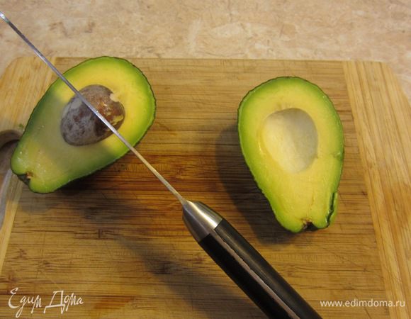 Прорежьте мякоть авокадо вокруг косточки. Покрутите одну половину авокадо по отношению к другой. Одна часть легко отделится от косточки. Осторожно ударьте лезвием по косточке. Лезвие воткнется. Поверните нож с косточкой и она отделится от мякоти.