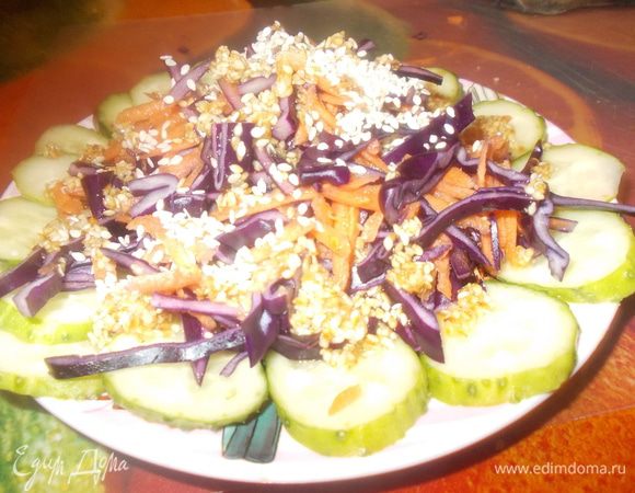 Колечки огурца укладываем на тарелку,сверху кладем капусту и морковь.Поливаем заправкой,посыпаем кунжутом.Подаем.