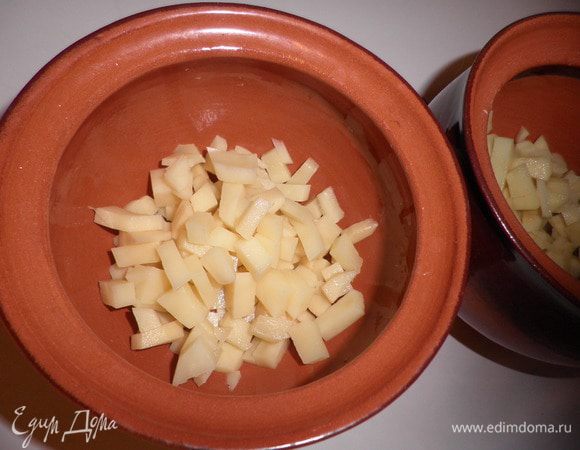 Картофель почистить и нарезать мелко на кубики, разложить поровну в 2 горшочка.