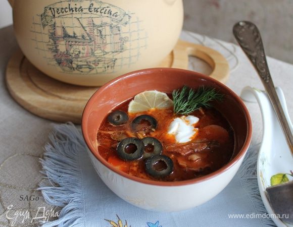 Готовую солянку разлейте по тарелкам, добавьте сметану, выложите по кружочку лимона, маслины или оливки. Украсьте зеленью.