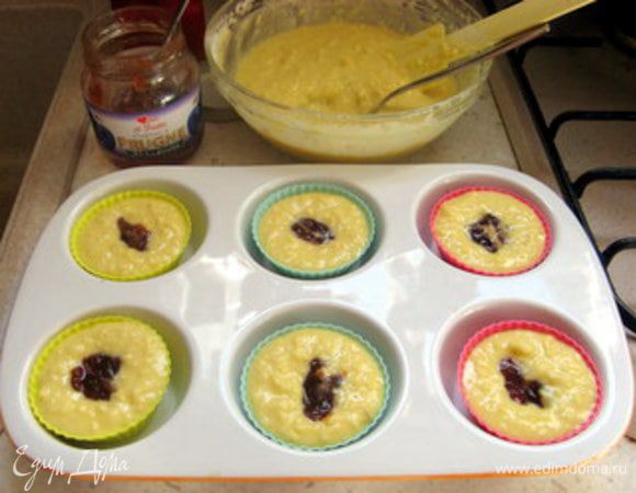 Чайной ложкой опустить в центр каждого маффина немного конфитюра.
