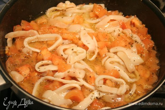 Кладем кольца кальмаров и томаты на сковороду, добавляем немного соли, базилика, чесночную кашицу и готовим 5 минут.