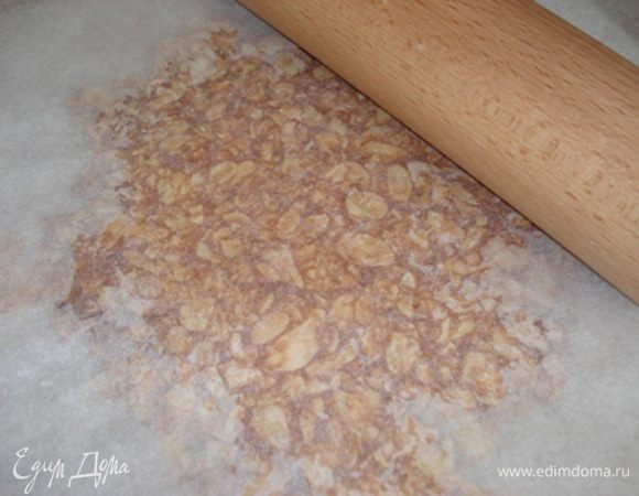 Пока они горячие,выложить на пергамент.Старайтесь распределить лепестки очень тонким слоем.У меня получился нугатин слишком толстый.В идеале он должн быть наполовину тоньше моего,поэтому при обрезании до нужной формы края получились неровные
Сверху положить второй лист пергамента и раскатать нугатин скалкой.