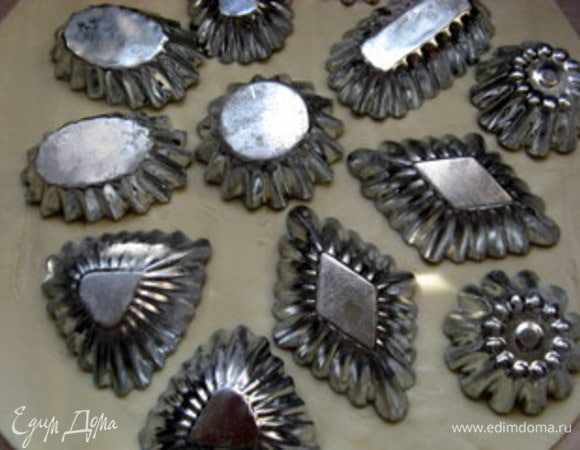 Через 40 минут тесто достать и раскатать его. Вырезать тесто по форме формочек. Если у вас формочки с волнистыми краями, вырезайте тесто на 5 мм  шире диаметра формочки. Так будет гораздо легче распределелять его по формочке.