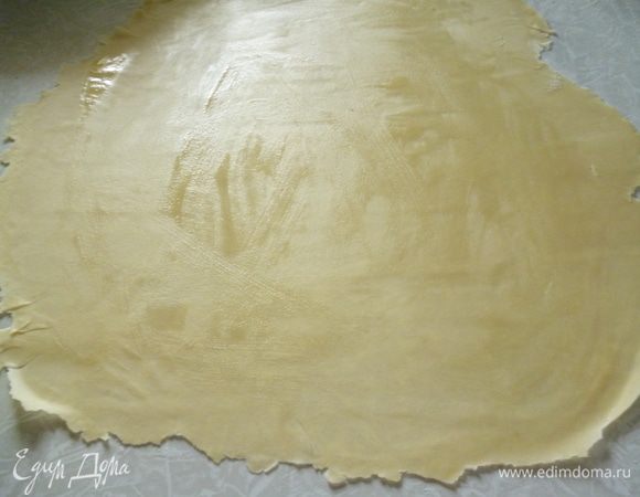 Затем раскатайте тесто скалкой от середины к краям в тоненький прямоугольный корж. Если края коржа будут не ровные, ничего страшного, все перекроется во время лепки. Смажьте поверхность теста растопленным сливочным маслом.