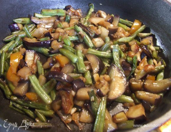 Обжарить баклажаны, фасоль и перец на подсолнечном масле на сковороде. Добавить 2 ст.л. соуса и мелко порубленный чеснок. Перемешать, выключить огонь и накрыть крышкой.