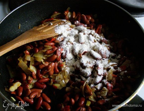 С фасоли сольем воду. К обжаренным овощам выложим фасоль, добавим растертый в ступке тмин и муку. Перемешаем. Посолим