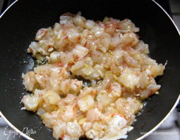 Обжарить лук на сливочном масле, добавить порезанные на кусочки креветки. 