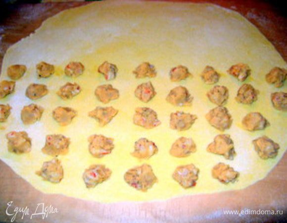 Раскатать тесто в тонкий, почти прозрачный, пласт.Разложить начинку ровными рядами (так будет легче нарезать на равиоли) на половину раскатанного пласта,(второй половиной нужно будет накрыть равиоли) оставляя около 2 см промежутки между начинкой. 