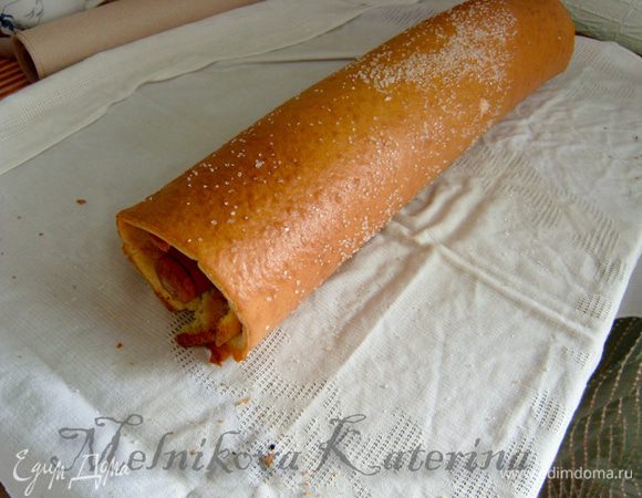 Аккуратно снять пергамент. Положить на бисквит скалку и скатать его вокруг скалки (чтобы он держал форму и не разломался, пока будет готовиться крем). 