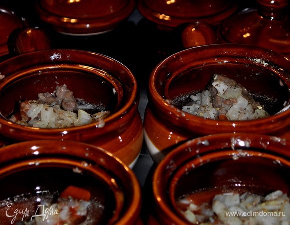 Подрумянить мясо в муке на сковороде.Разложить в горшочки, добавить измельченный лук,томатное пюре,соль и перец по вкусу.Залить горячим бульоном и закрыть крышками.