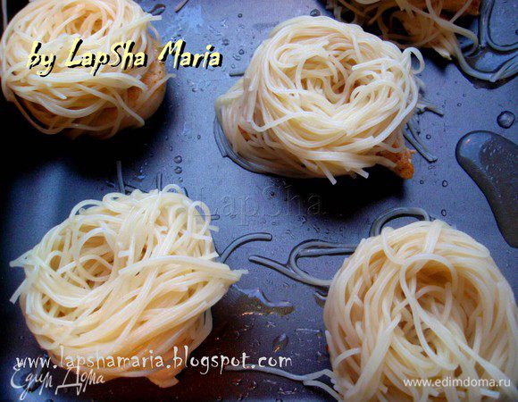 На противень или в форму выкладываем кусочки мяса, оставляя между ними промежуток. Сверху готовые гнезда из спагетти.