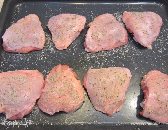 Возьмите противень, в котором будете запекать бедра. Положите туда курицу, посыпьте сверху смесью приправ.