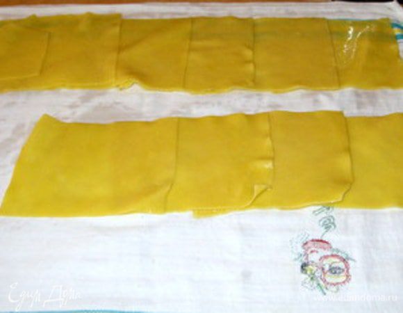 Накрыть рабочую поверхность кухонным полотенцем. Разложить на полотенце прямоугольники из пасты, накладывая один на другой по нескольку в ряд.